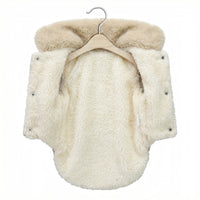 Cream-colored fluffy garment on a hanger against a white background