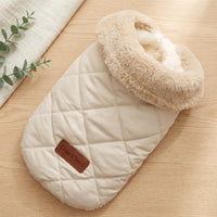 White quilted baby bag with beige fur hood on a wooden surface, featuring a brand logo.